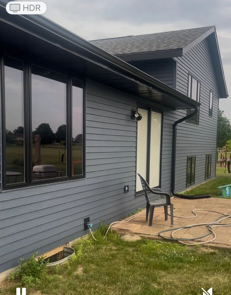 Modern home addition with metal roof, gray siding, and large windows in Leaf River