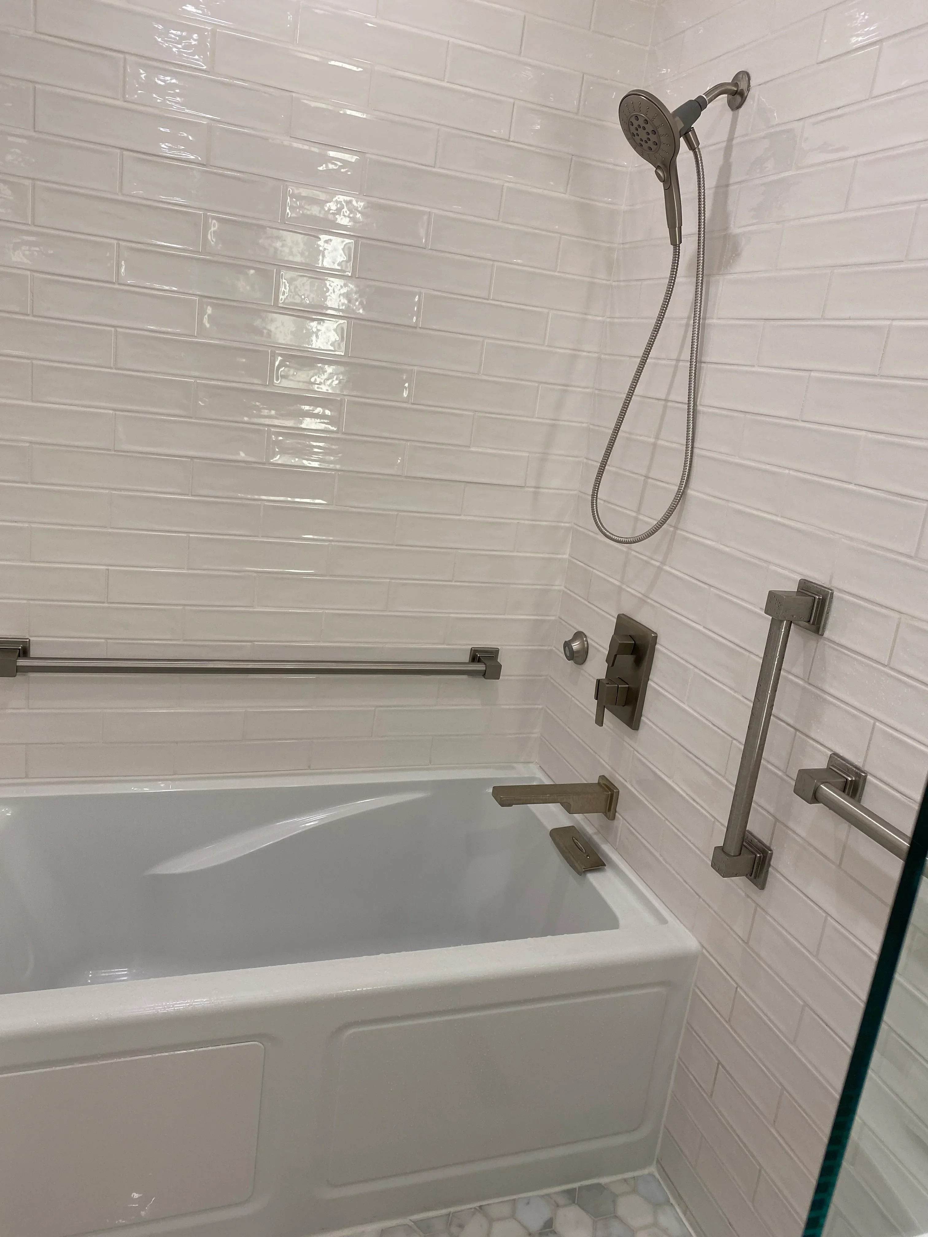Modern bathroom with white subway tile walls, brushed nickel fixtures, and soaking tub